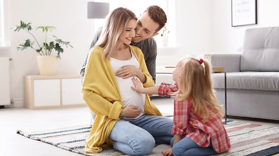 Junge schwangere Frau mit ihrer Familie Zuhause